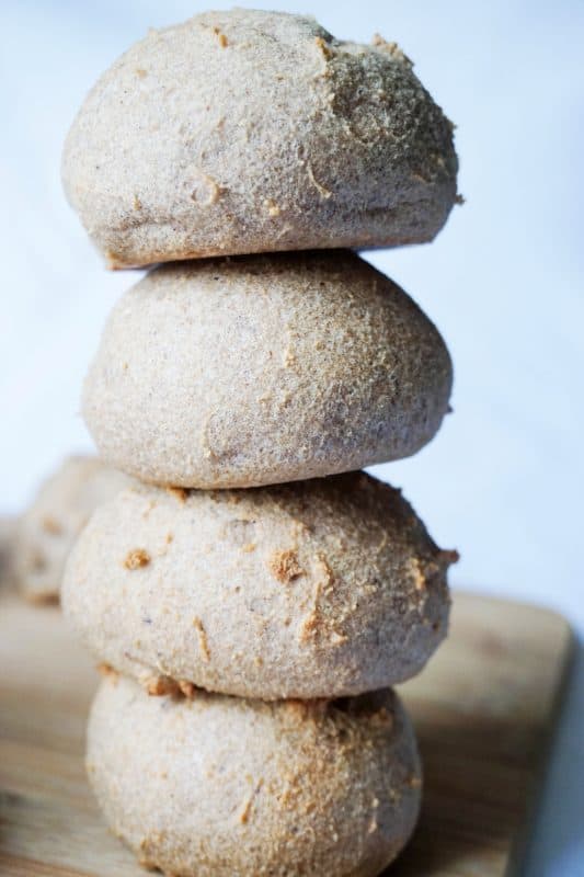 A stack of three round bread rolls on a wooden board.