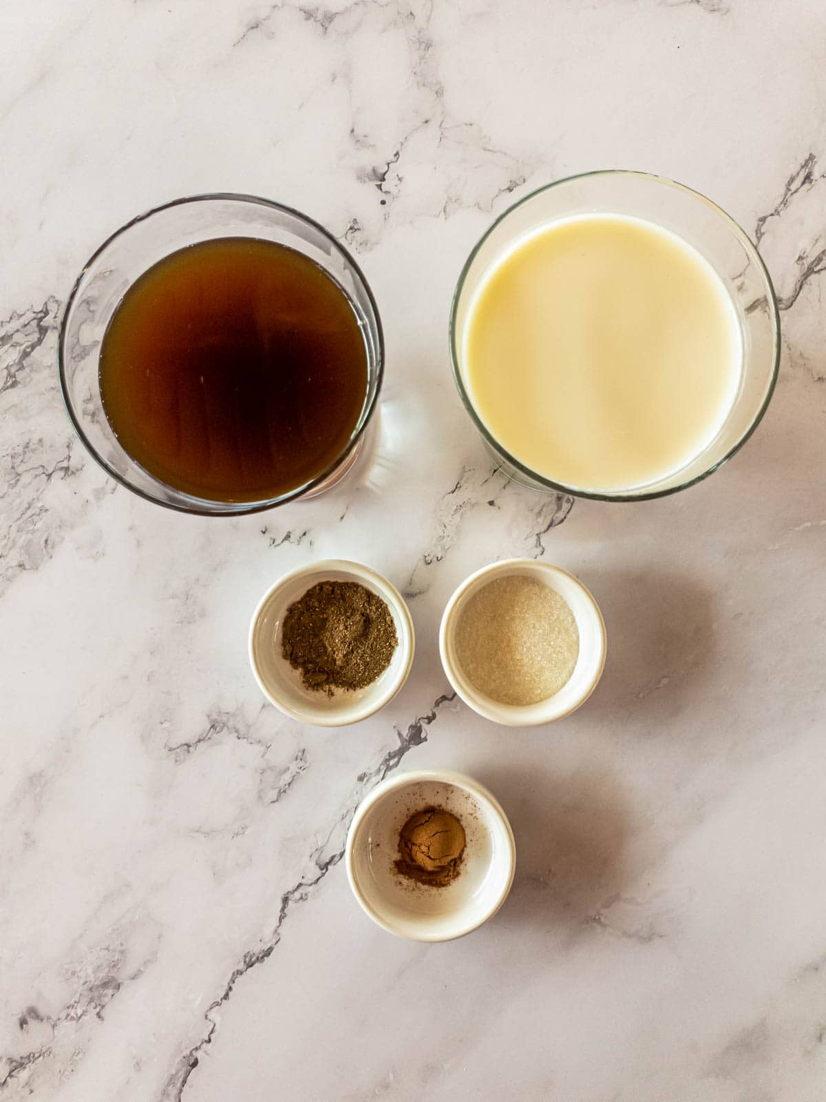 Ashwagandha coffee ingredients arranged over marble background in individual bowls.
