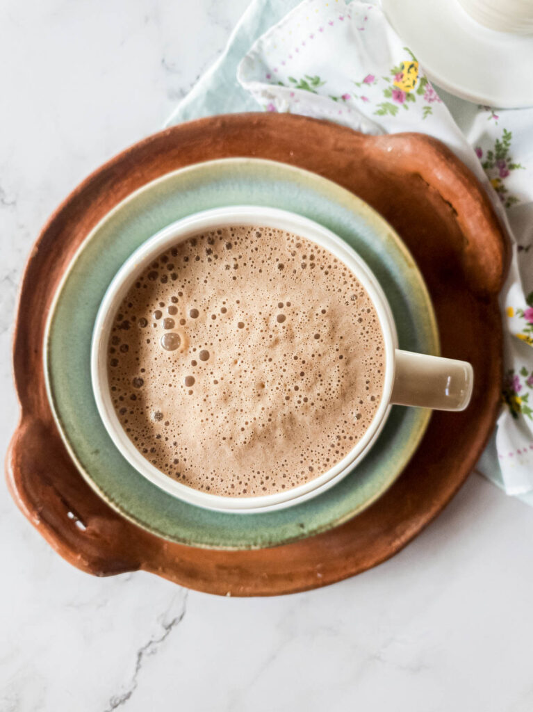 A picture of hot broth latte on marble background with tera cotta tray.