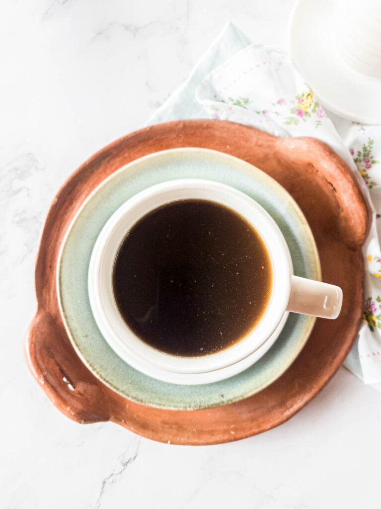 A picture of broth and coffee in mug together.