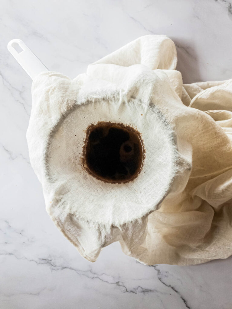 A picture of cheesecloth resting over a strainer and jar.