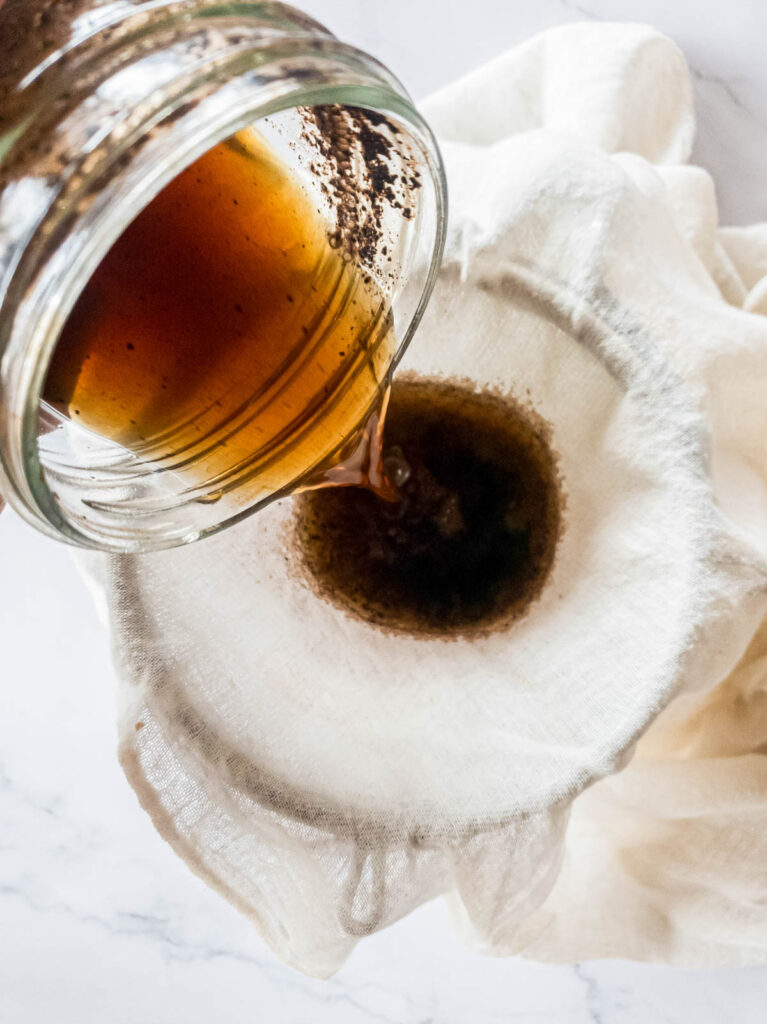 A picture of cold brew being strained through cheesecloth.