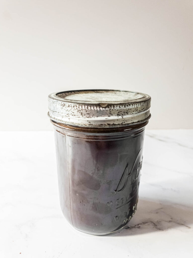 A picture of ground coffee infusing in glass mason jar.