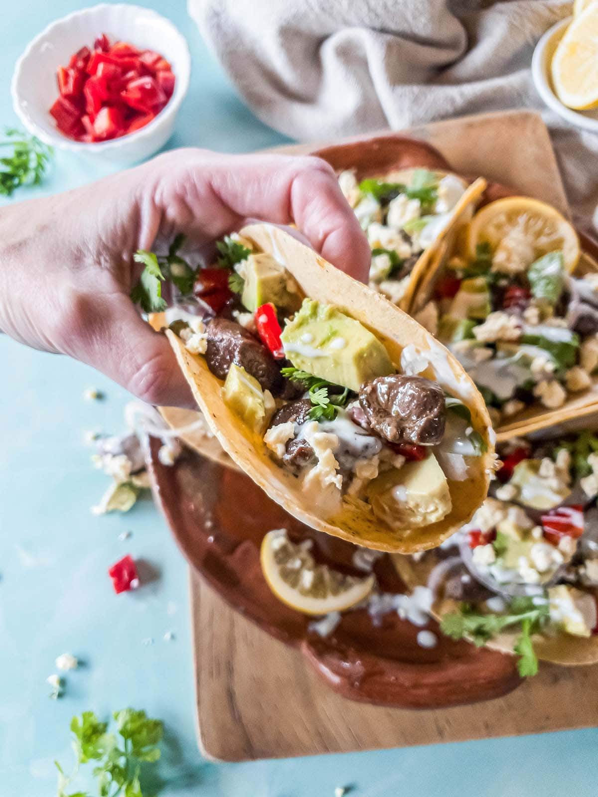 A woman's hand holding fresh beef taco, ready to eat.