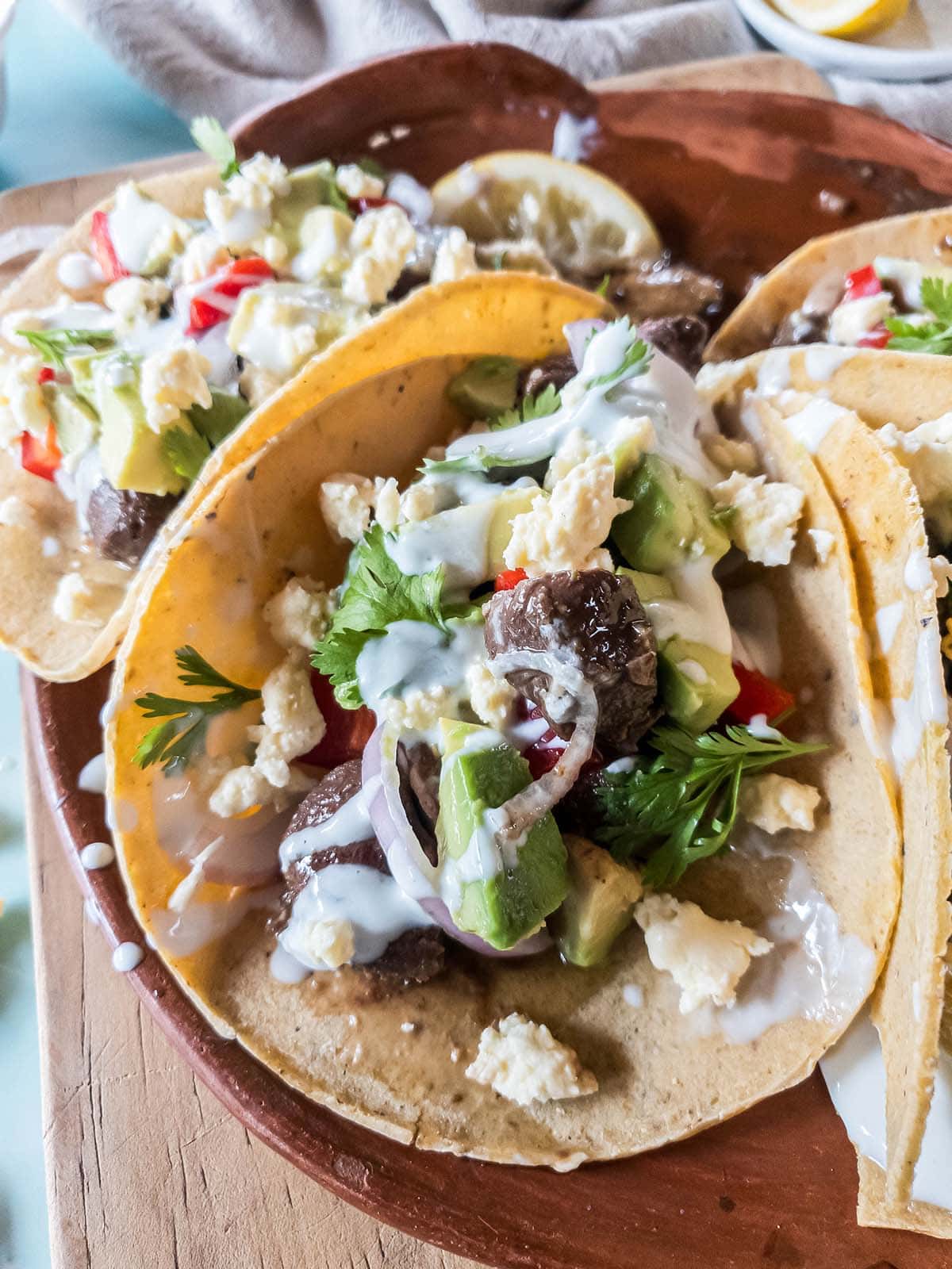 Healthy beef tacos on a ceramic tray on a wooden board.