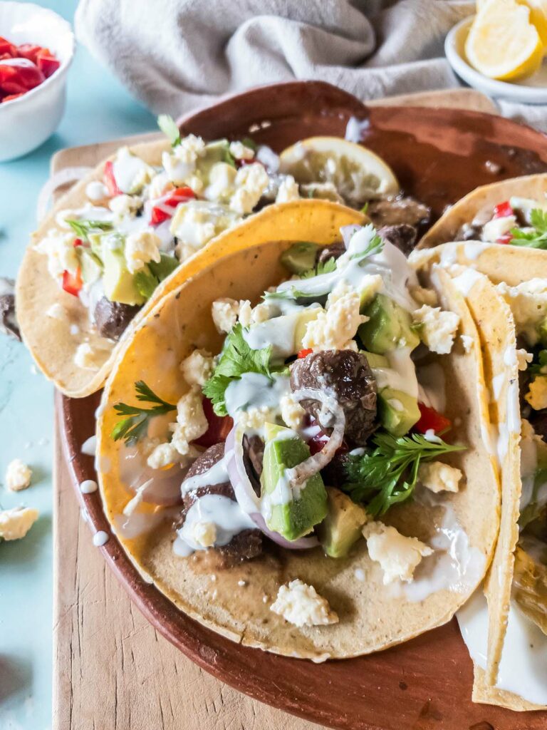 Quick beef tacos in corn tortillas on a tray and cutting board.