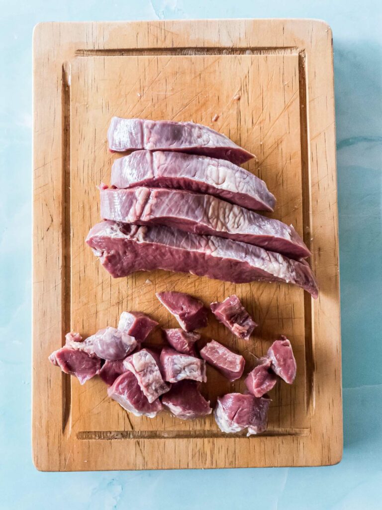 A picture of trimmed, diced raw heart on a cutting board.