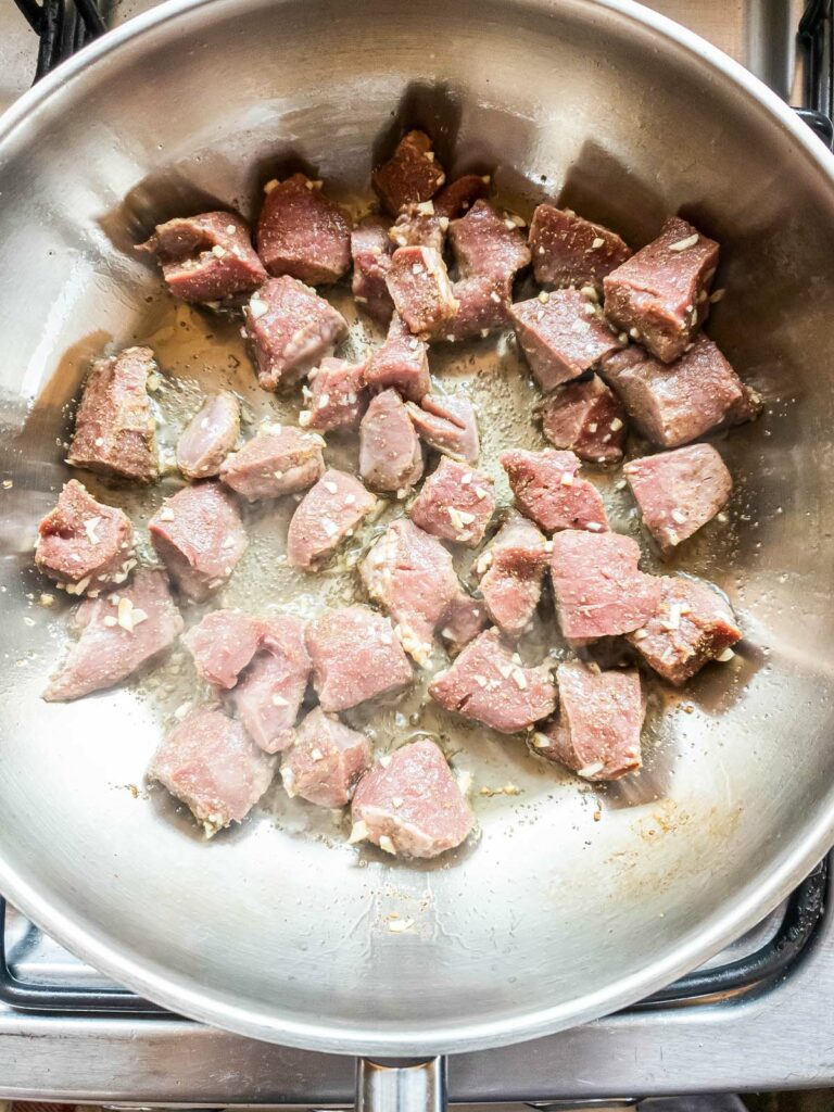 Diced beef heart in garlic butter in skillet.