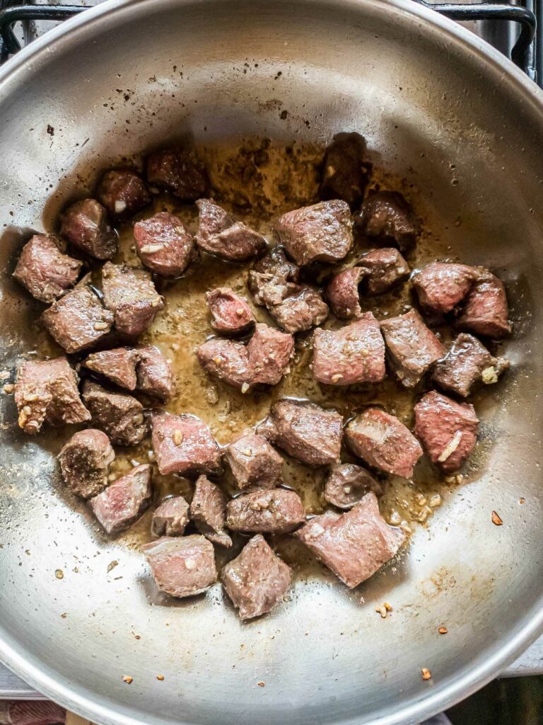 Diced beef heart cooking in a frying pan.