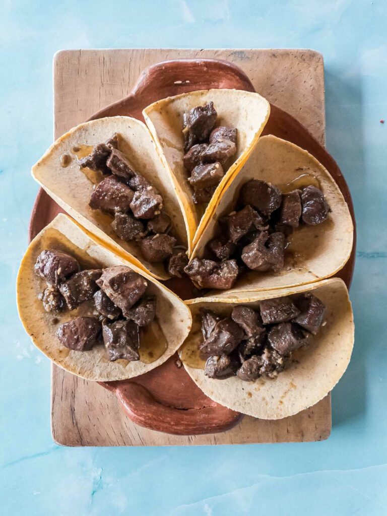 A picture of browned beef heart in corn tortillas.