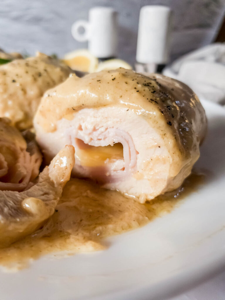 A plate of chicken cordon bleu no breading cut in half on a white plate.