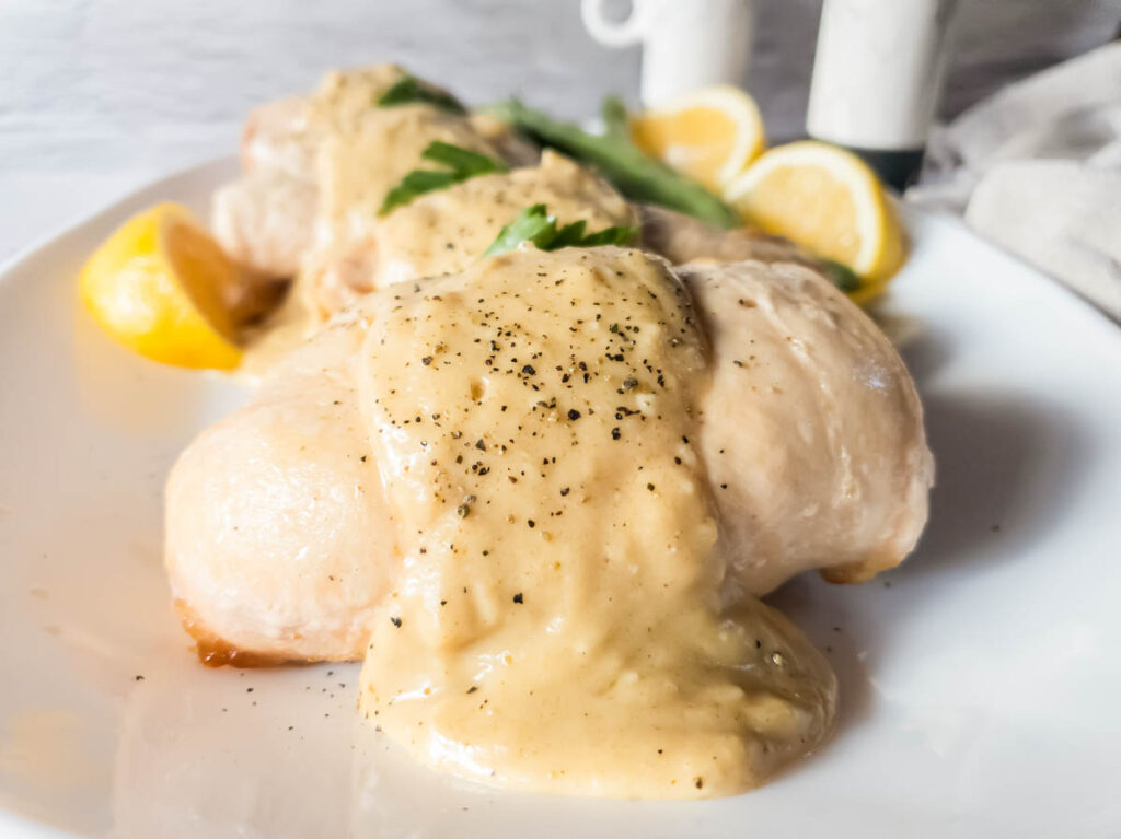 Stuffed chicken breast with black pepper and sauce on a white plate.