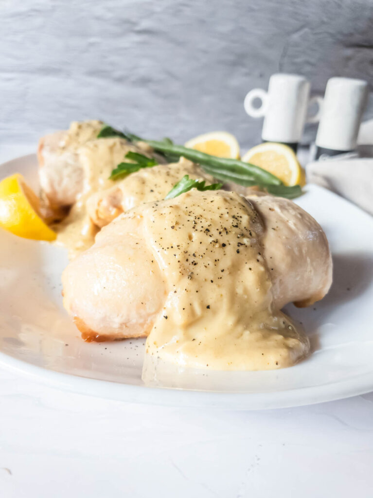 Chicken breasts with alfredo cheese sauce on a white plate.