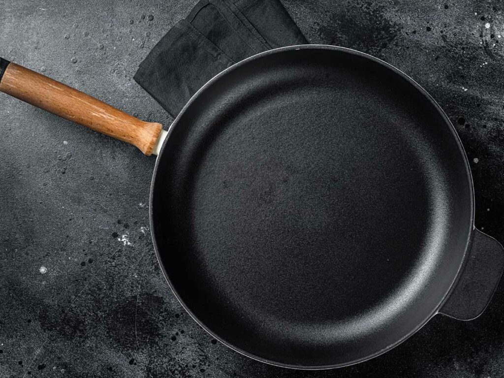 A black cast iron skillet pan with a wooden handle.