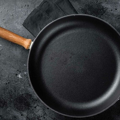 A black cast iron skillet pan with a wooden handle.