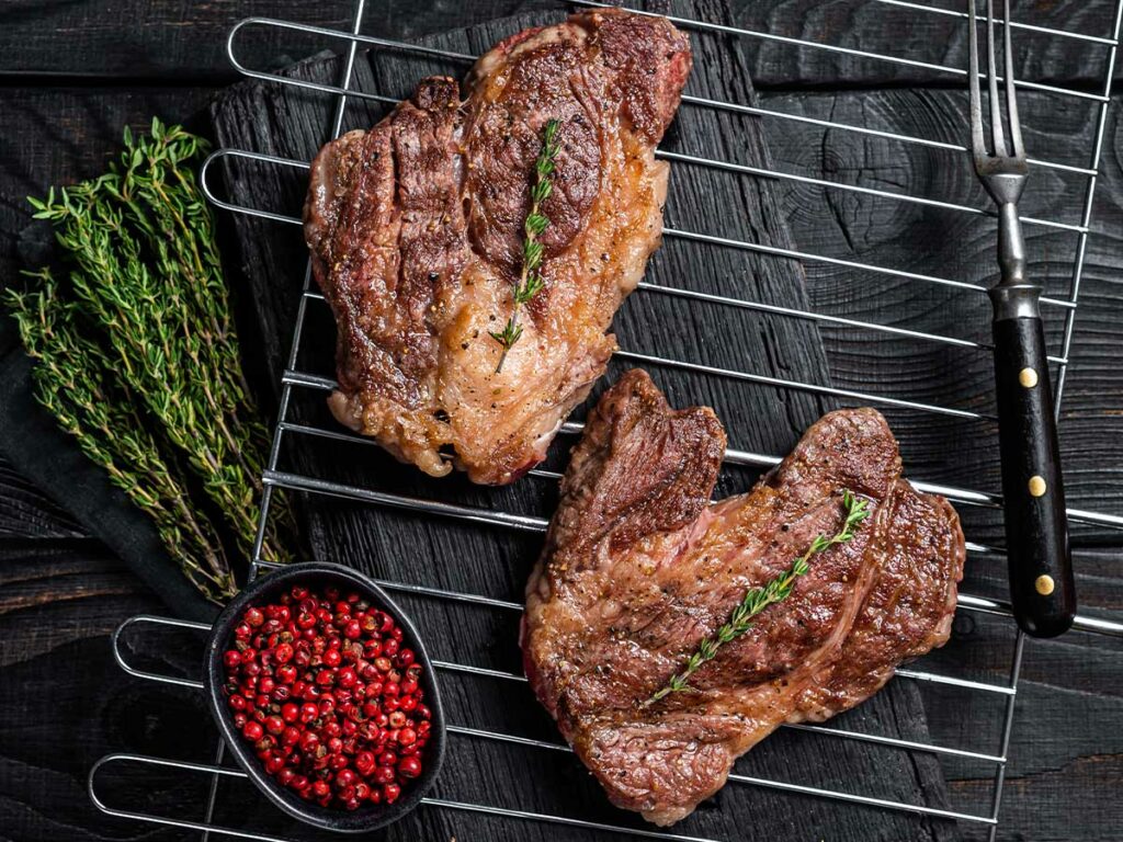 Two steaks on a rack on a black background.