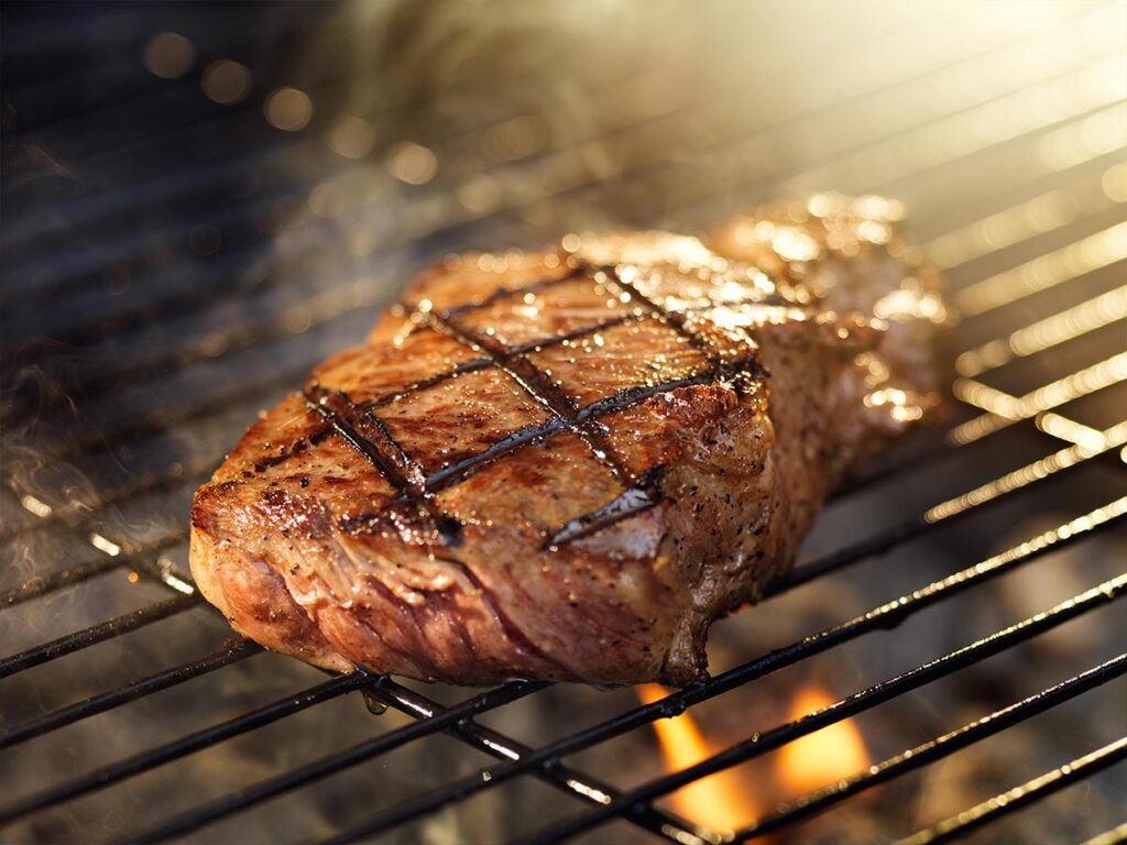 A steak is being cooked on a grill.