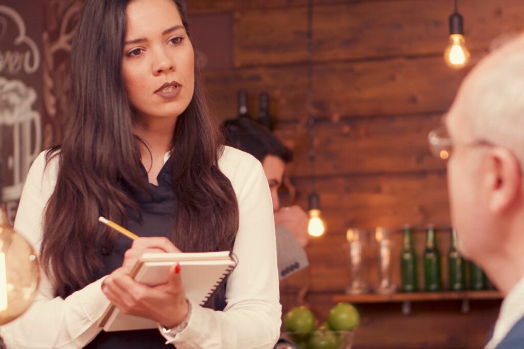 A female server writing down order at restaurant.