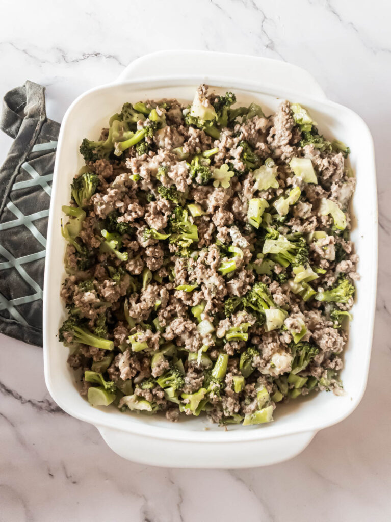 A white dish with meat and broccoli in it.