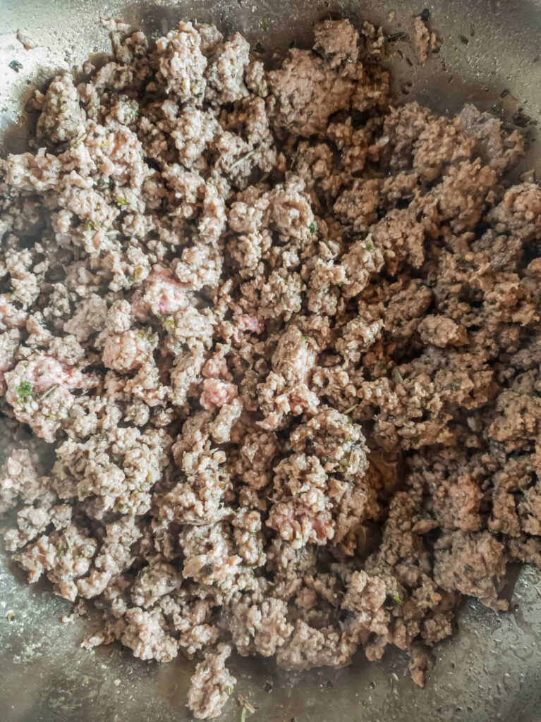 Browned ground beef in a pan on a stove top.