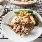 A keto meat pie with green beans on a plate, close up on bite.