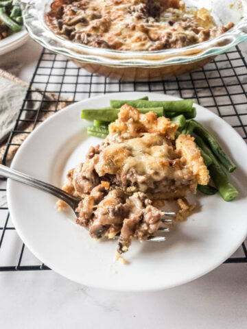 A keto meat pie with green beans on a plate, close up on bite.
