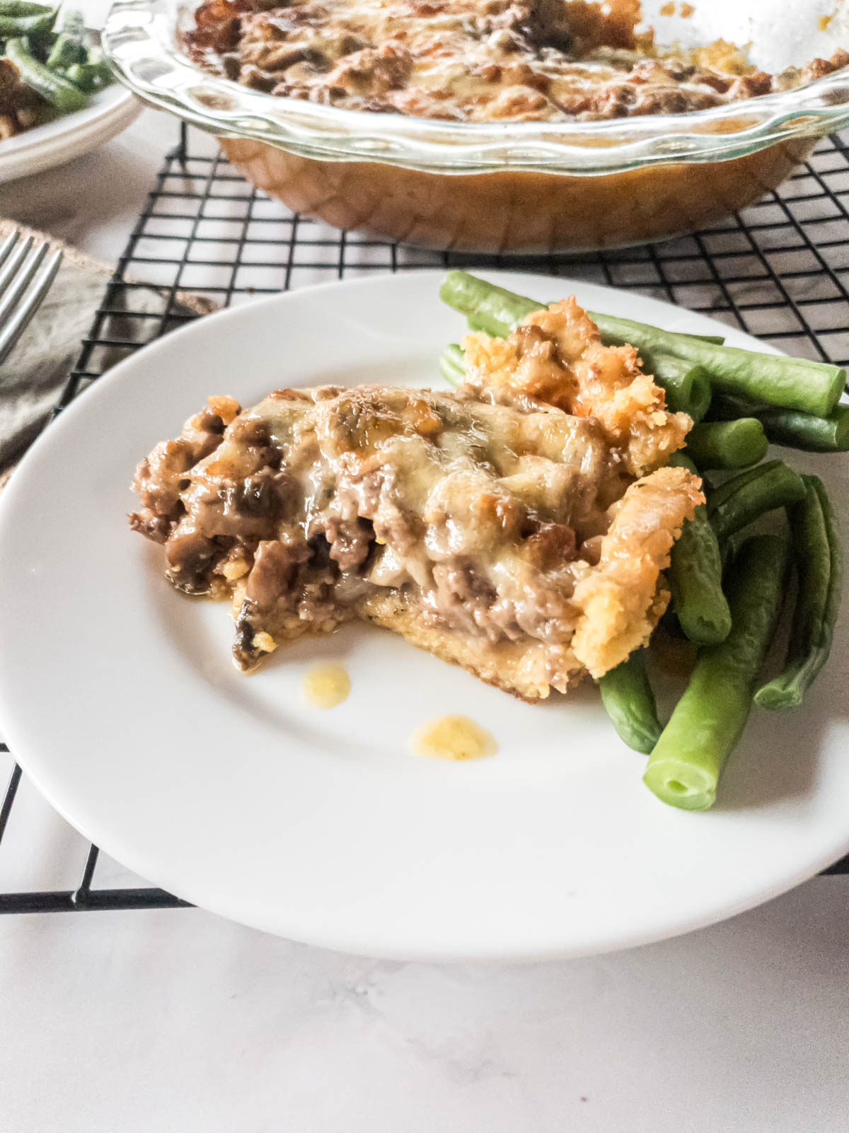 A keto-friendly meat pie with green beans on a plate.