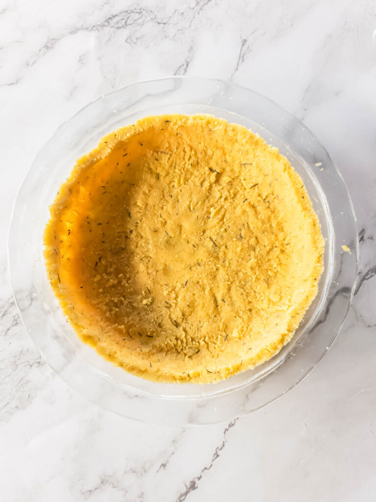 A savory keto pie crust pressed into a glass baking dish.