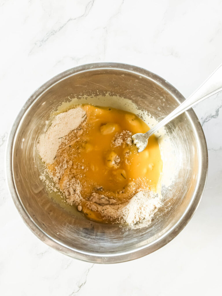 A bowl containing a mixture of beaten eggs and flour with a fork