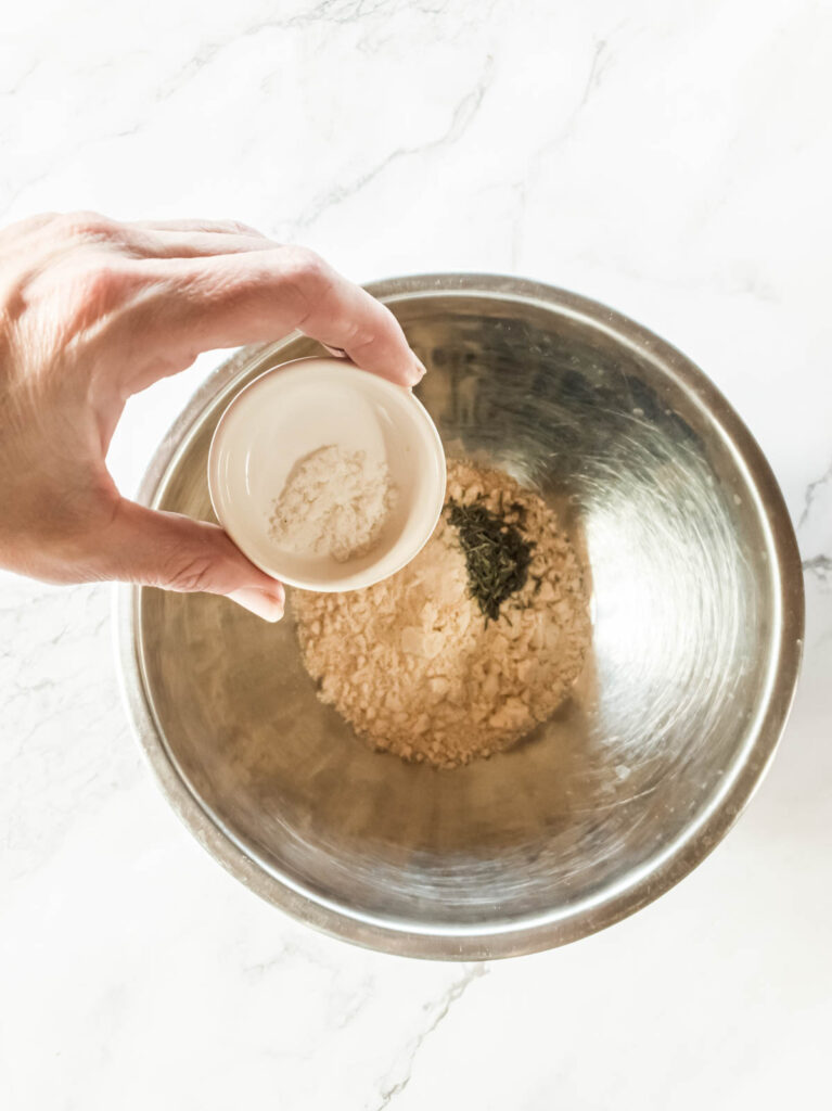 A person pouring salt into the bowl of dry ingredients.