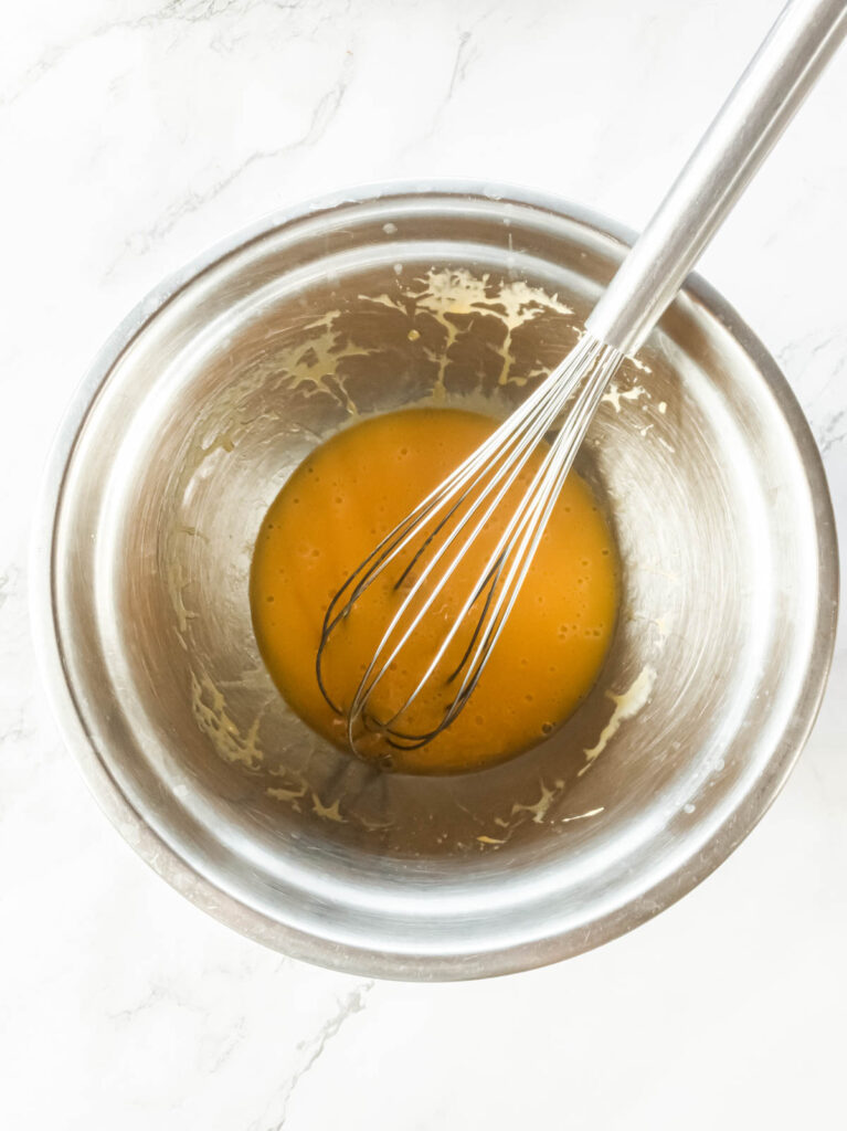 Whisking eggs in a silver mixing bowl.