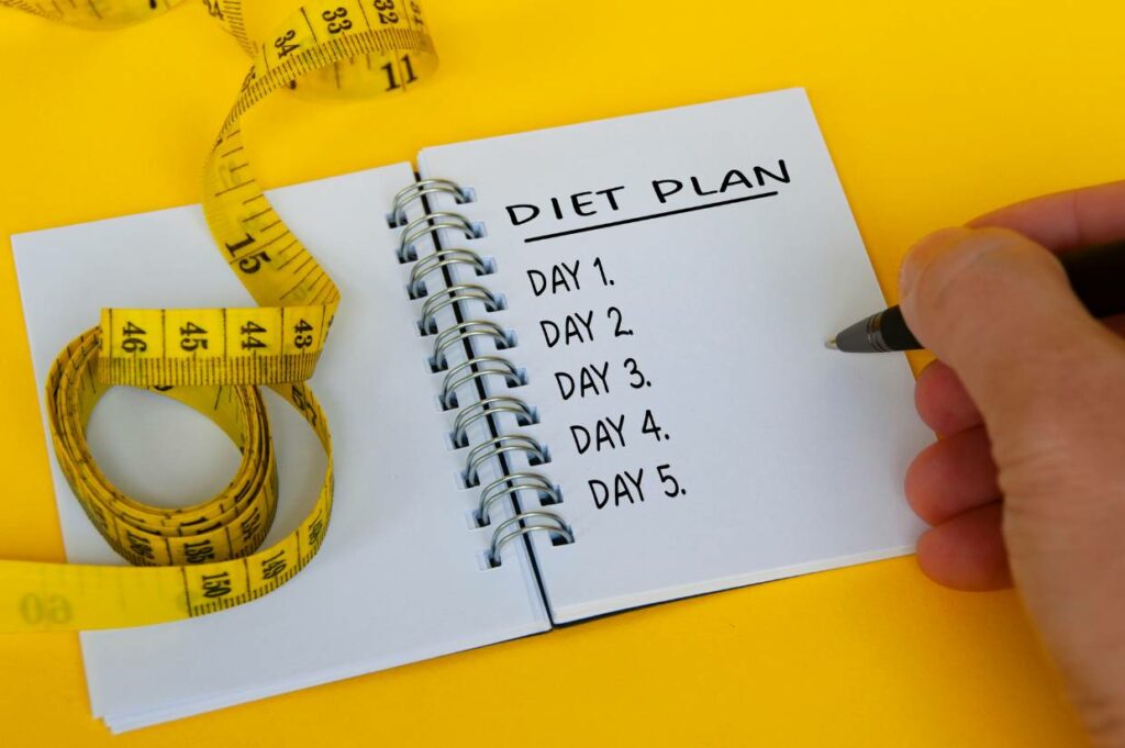 A person diligently jotting down an elimination diet plan on a notebook.