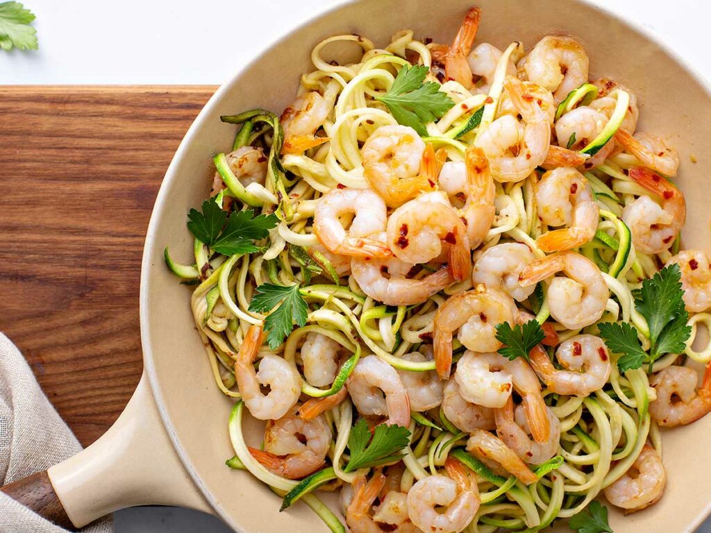 Shrimp and zucchini noodles in a skillet.