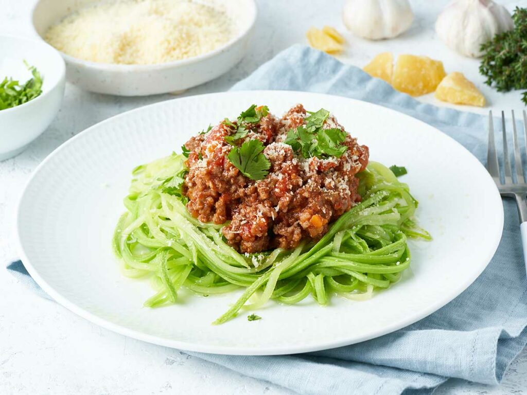 A plate with zoodle spaghetti and meat on it.
