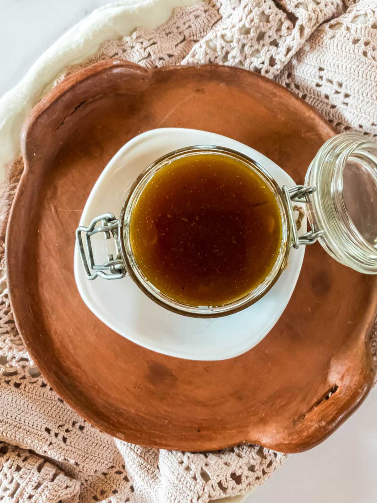 A jar of sugar-free pumpkin spice syrup on a terra cotta plate.