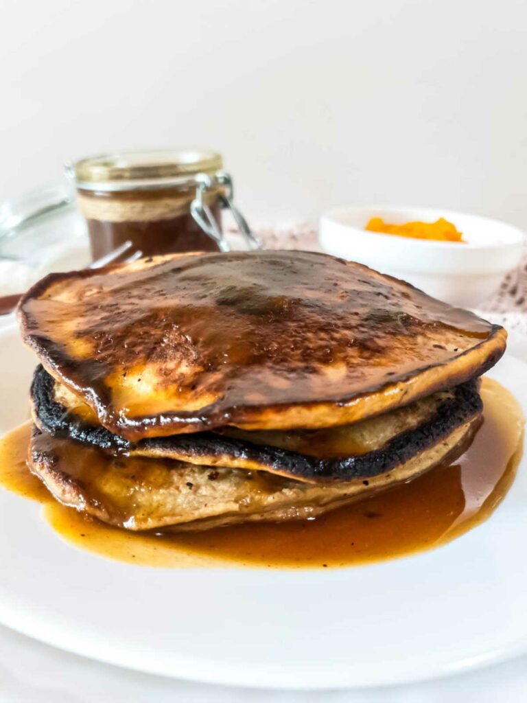 A stack of pancakes with syrup on a plate.