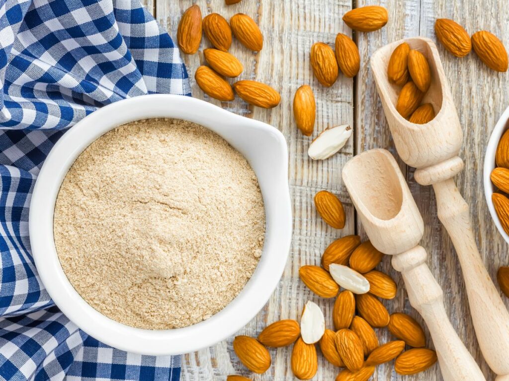 Almond flour and almonds on a wooden table.