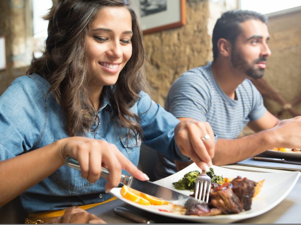 A man and a woman eating a plate of food at a restaurant.