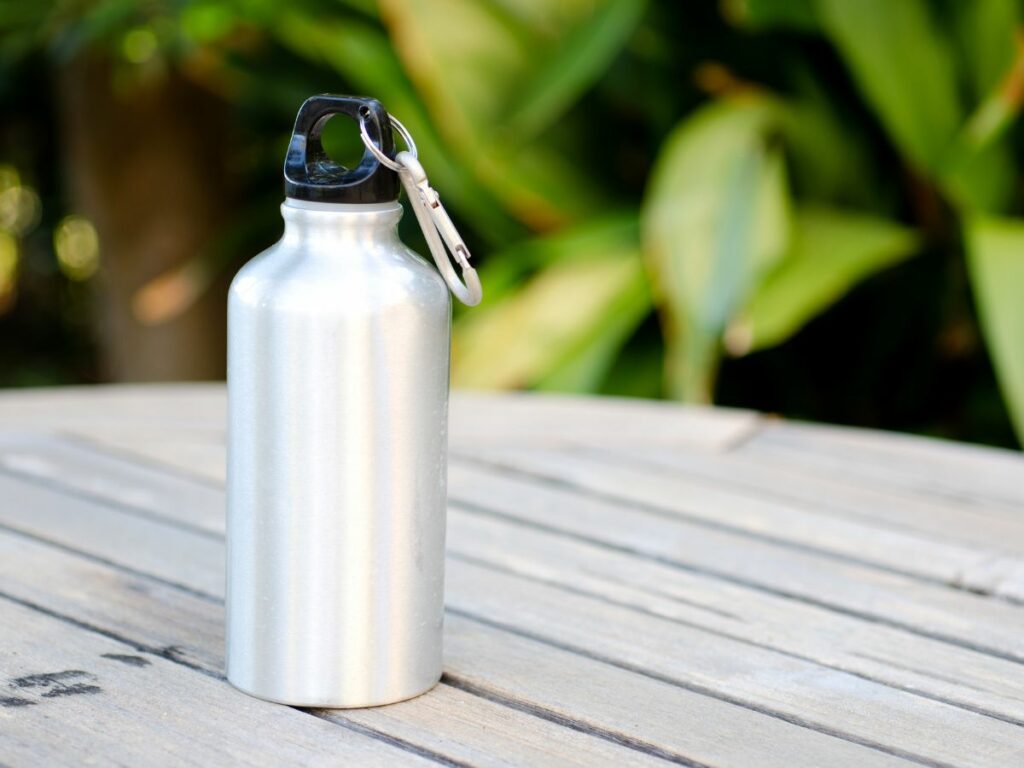 A steel water bottle sitting on a wooden table.