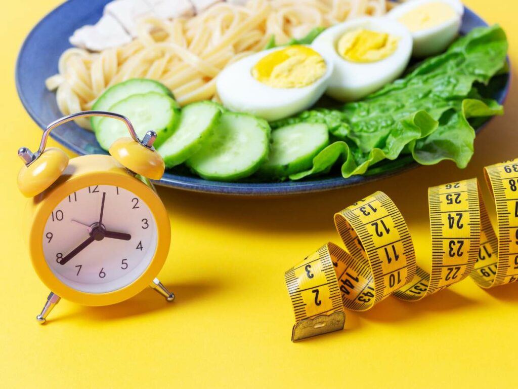 A plate with noodles and an alarm clock on a yellow background.