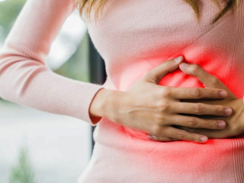 A woman holding her stomach with a red light on it.