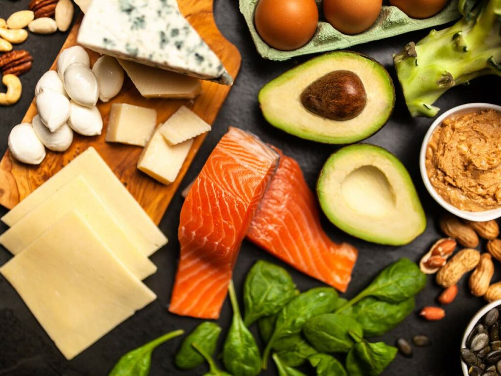A variety of foods including salmon, eggs, avocado, nuts, and spinach.