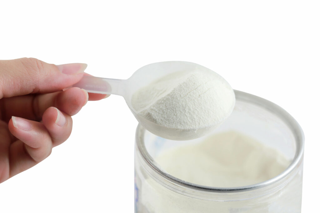A hand holding a scoop of collagen powder.