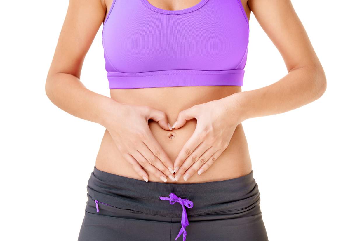 Woman making a heart shape with her hands on her stomach.