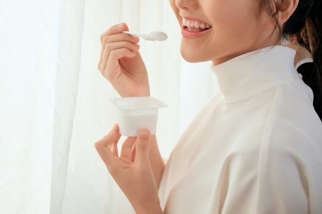 Woman smiling while eating yogurt.