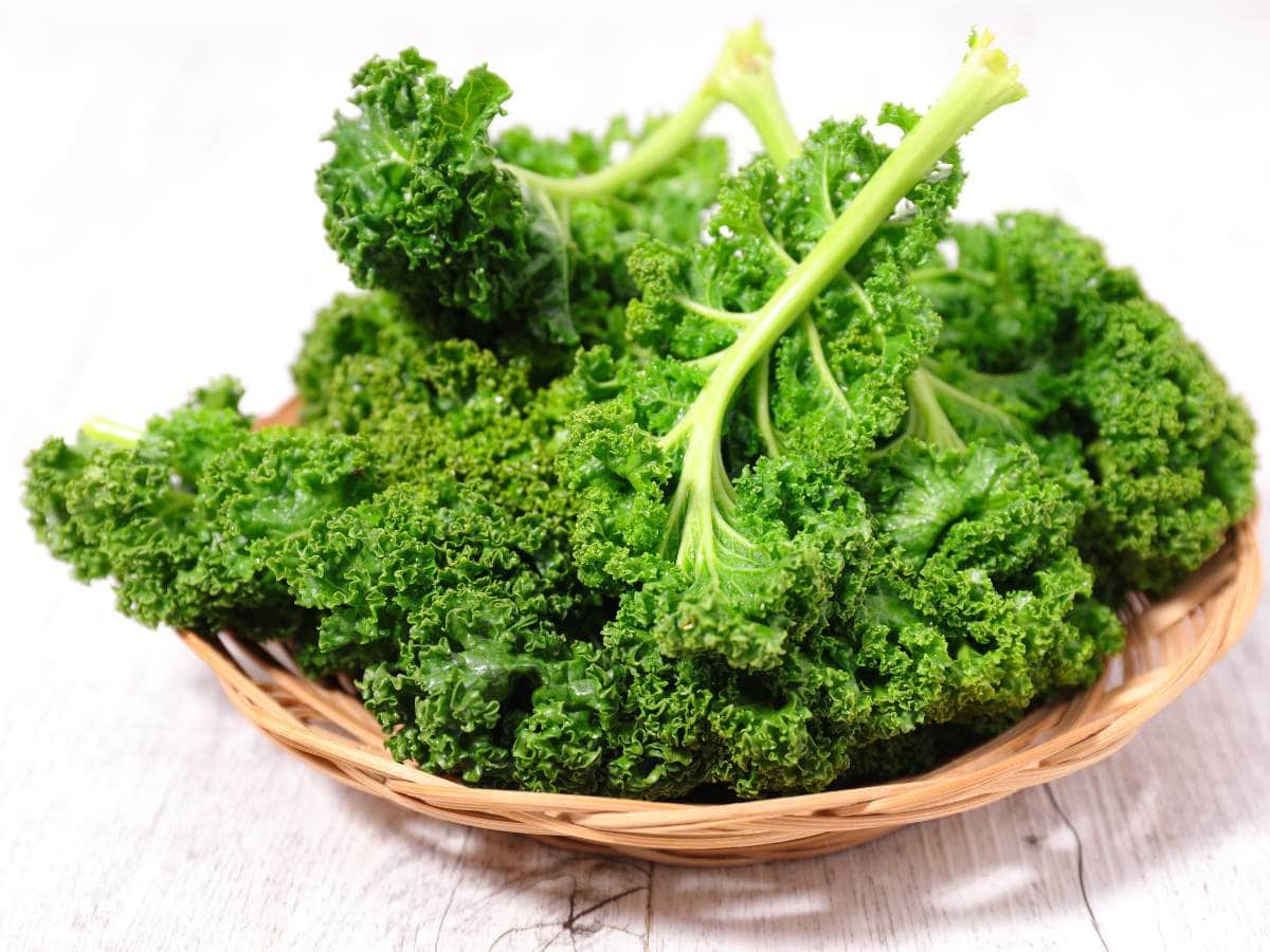 Kale in a wicker basket on a wooden table.