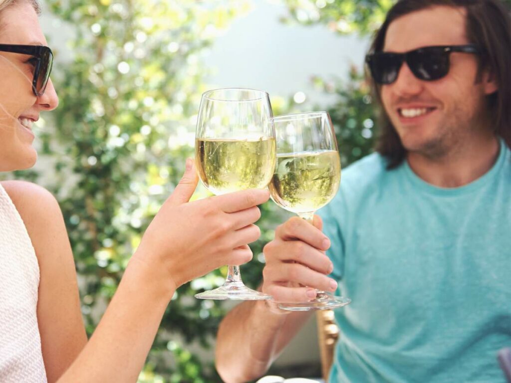 A man and woman toasting glasses of wine outdoors.