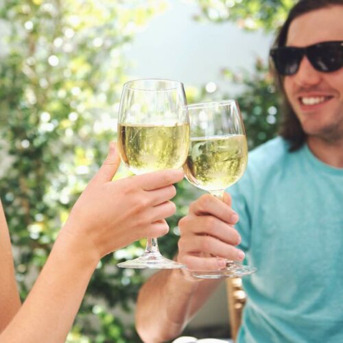 A man and woman toasting glasses of wine outdoors.