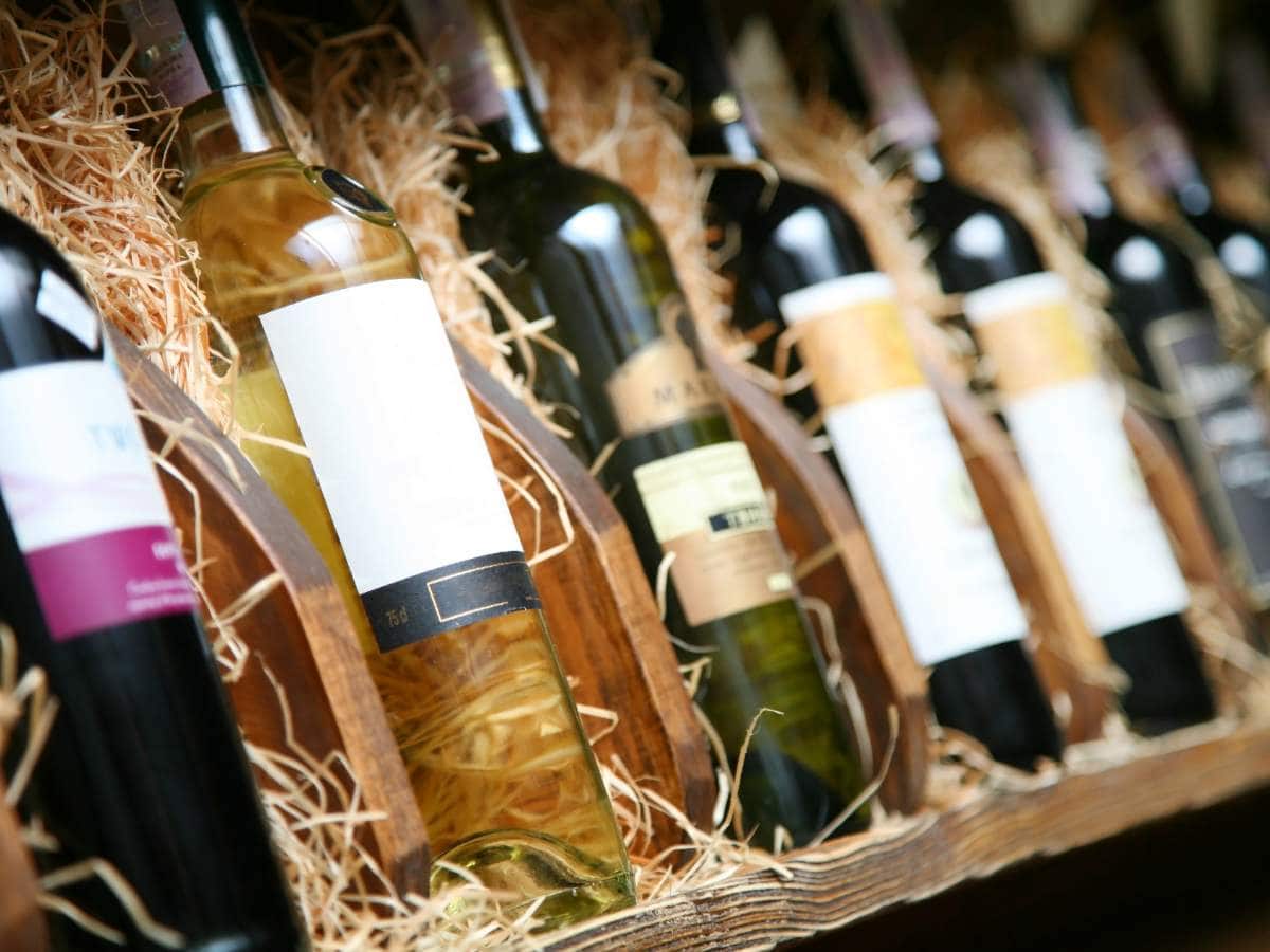 A row of wine bottles lined up on a wooden shelf.