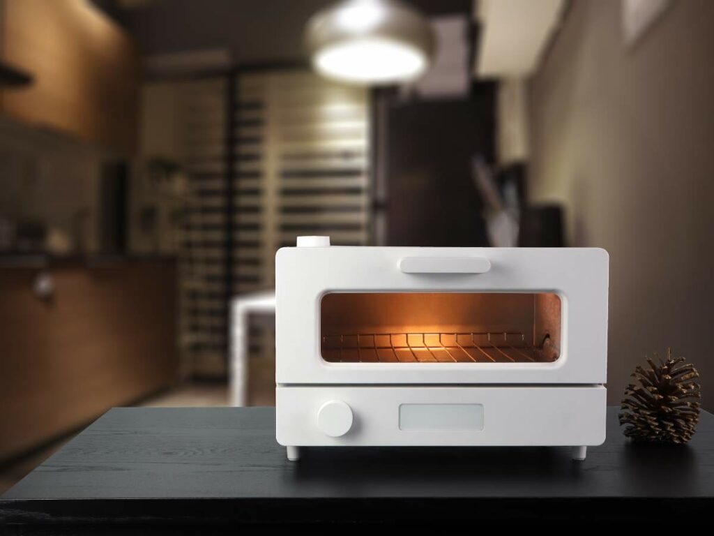 A modern toaster with a slice of bread inside, placed on a kitchen counter.